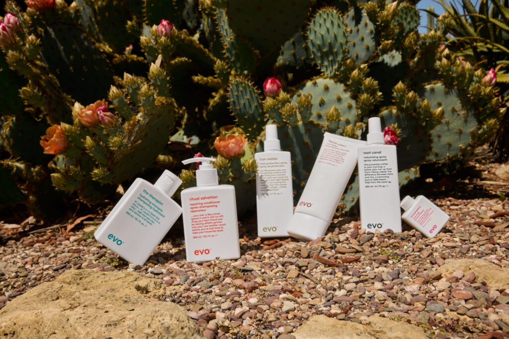Een reeks Evo-haarverzorgingsproducten is uitgestald in een woestijnlandschap met cactussen op de achtergrond.