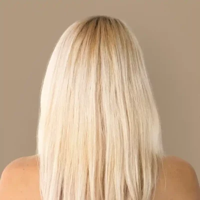 Achteraanzicht van lang, steil blond haar tegen een neutrale achtergrond.
