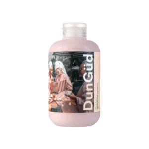 Roze fles DunGüd Day Spa Restorative Shampoo met een etiket waarop vrouwen in badjassen ontspannen bij een spa.