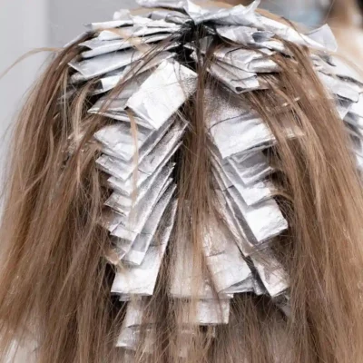 Blond haar met folies tijdens het kleuren bij de kapper.