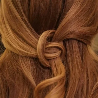Een close-up van koperkleurig haar dat in een sierlijke knoop is gevlochten.