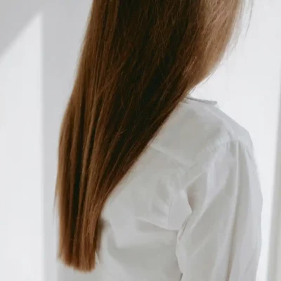 Vrouw met lang, steil en niet-gekleurd bruin haar in een witte blouse.