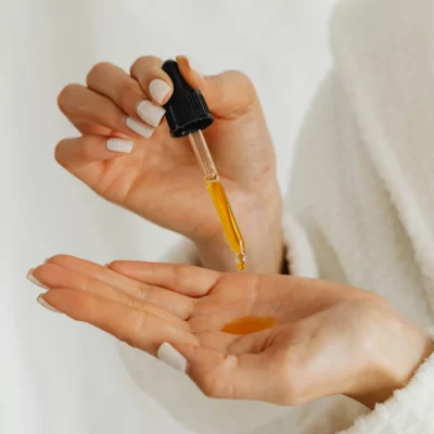 Vrouw druppelt styling-olie uit een pipetflesje in haar hand.
