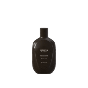 Zwarte fles Urban Alchemy Smooth Satin conditioner met minimalistisch etiket op een zwarte achtergrond.