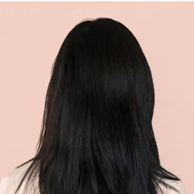 Achteraanzicht van lang, steil zwart haar tegen een roze achtergrond.